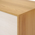 Close-up of a mid-century modern dresser corner, showcasing a combination of light and dark wood grain textures.