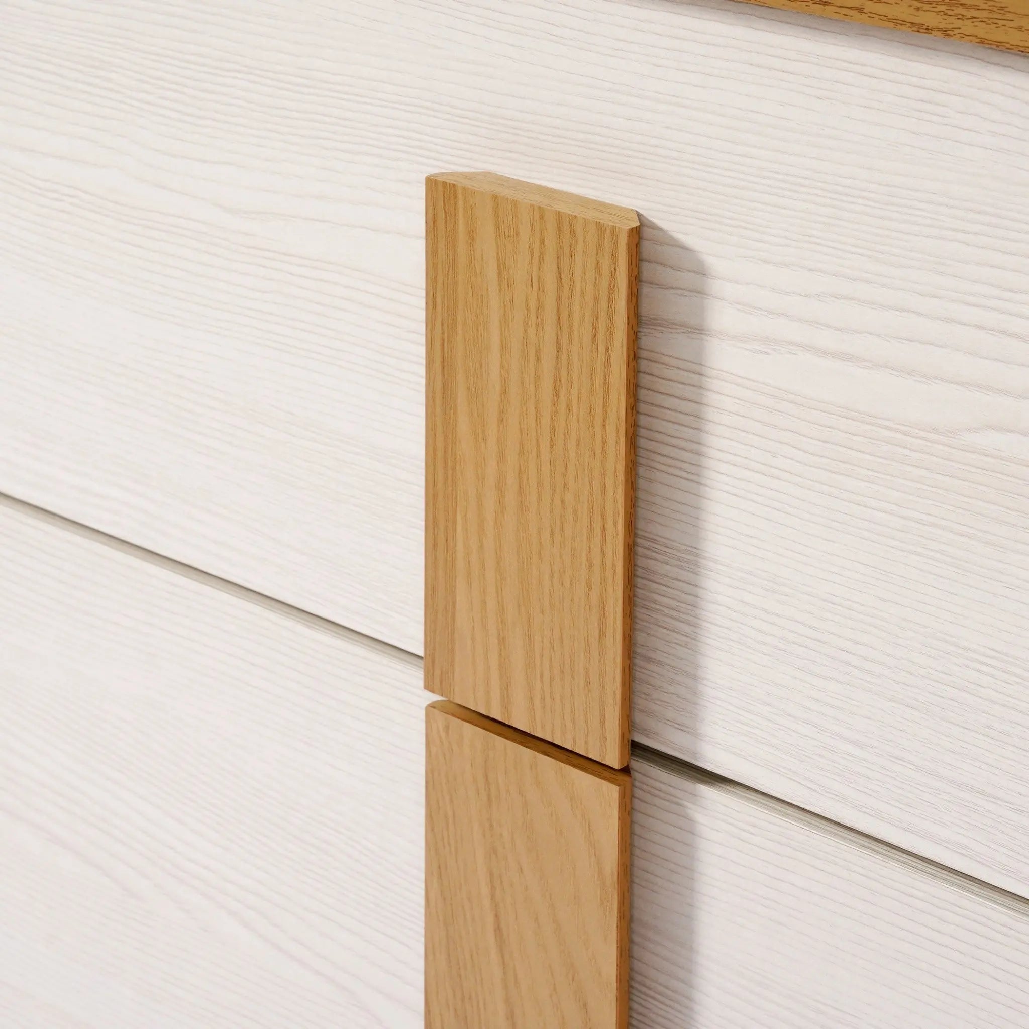 Close-up of a wooden handle on a light-colored drawer, showcasing the texture and grain of the wood in this mid-century modern design. Perfect for those seeking a stylish storage solution with its elegant 4-drawer chest configuration.