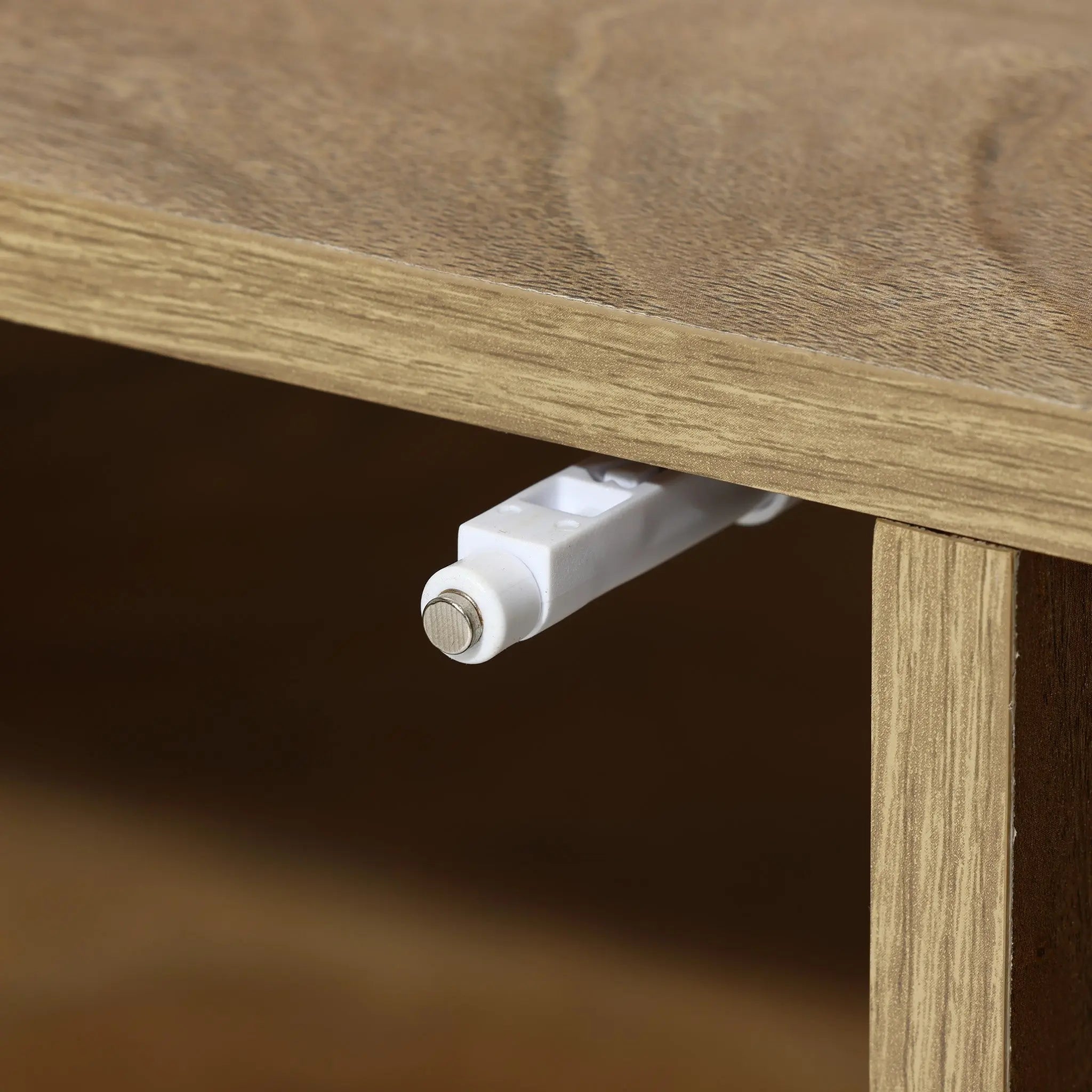 Close-up of a mid-century modern wooden cabinet in light walnut-colored wood, featuring a protruding white plastic hinge or stopper on the edge.