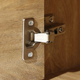 Close-up of a metal hinge on a wooden cabinet door, partially open, revealing the light walnut-colored wood that embodies a mid-century modern charm.