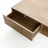 A wooden drawer partially open, revealing an empty interior, suggests hidden storage space. The drawer is part of a light wood piece of furniture with a mid-century modern design against a white background.