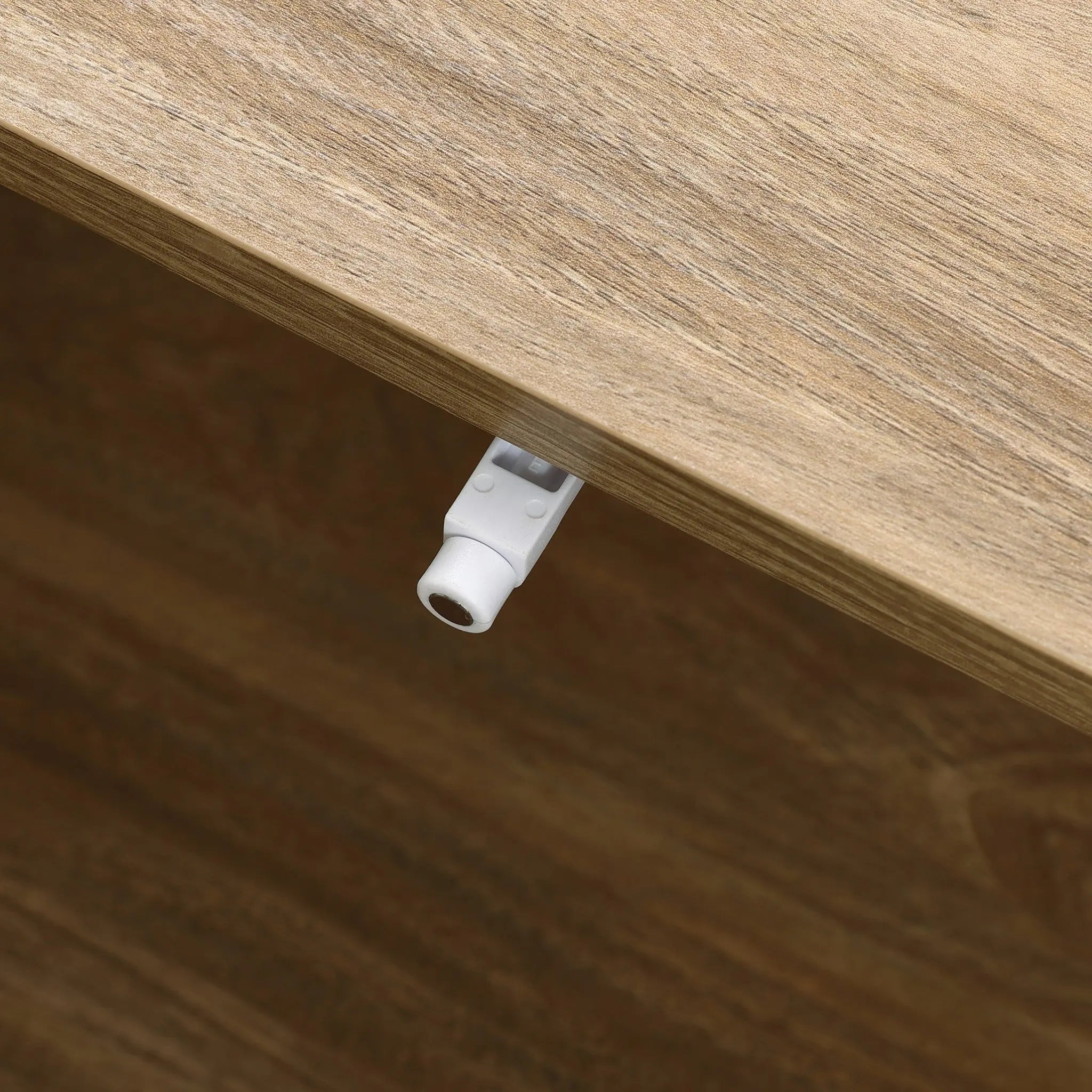A close-up of a wooden surface on a mid-century modern coffee table showcases a small white plastic latch neatly attached to the side.