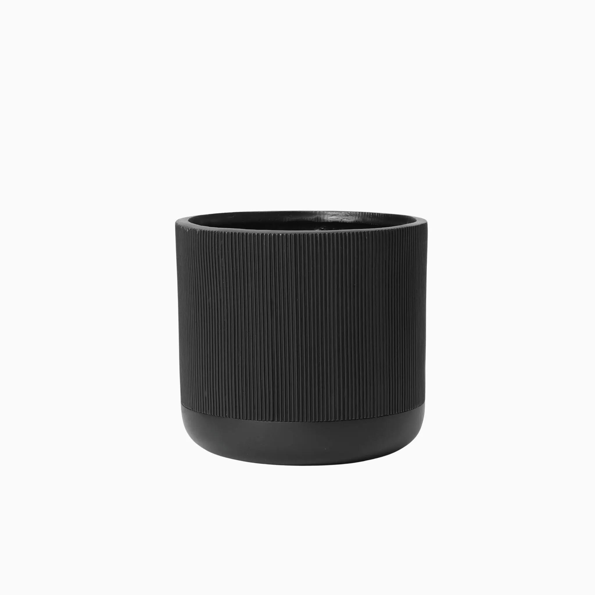 A black cylindrical ribbed planter, crafted from durable magnesium oxide material, sits elegantly against a white background.