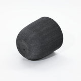 A cylindrical, textured air filter with a dark base, reminiscent of minimalist design planters, is showcased against a white background.