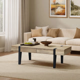 A modern living room features a light beige sofa with matching pillows, an oak finish wood modern farmhouse coffee table with black legs, and framed landscape artwork above the sofa on a neutral-colored rug.