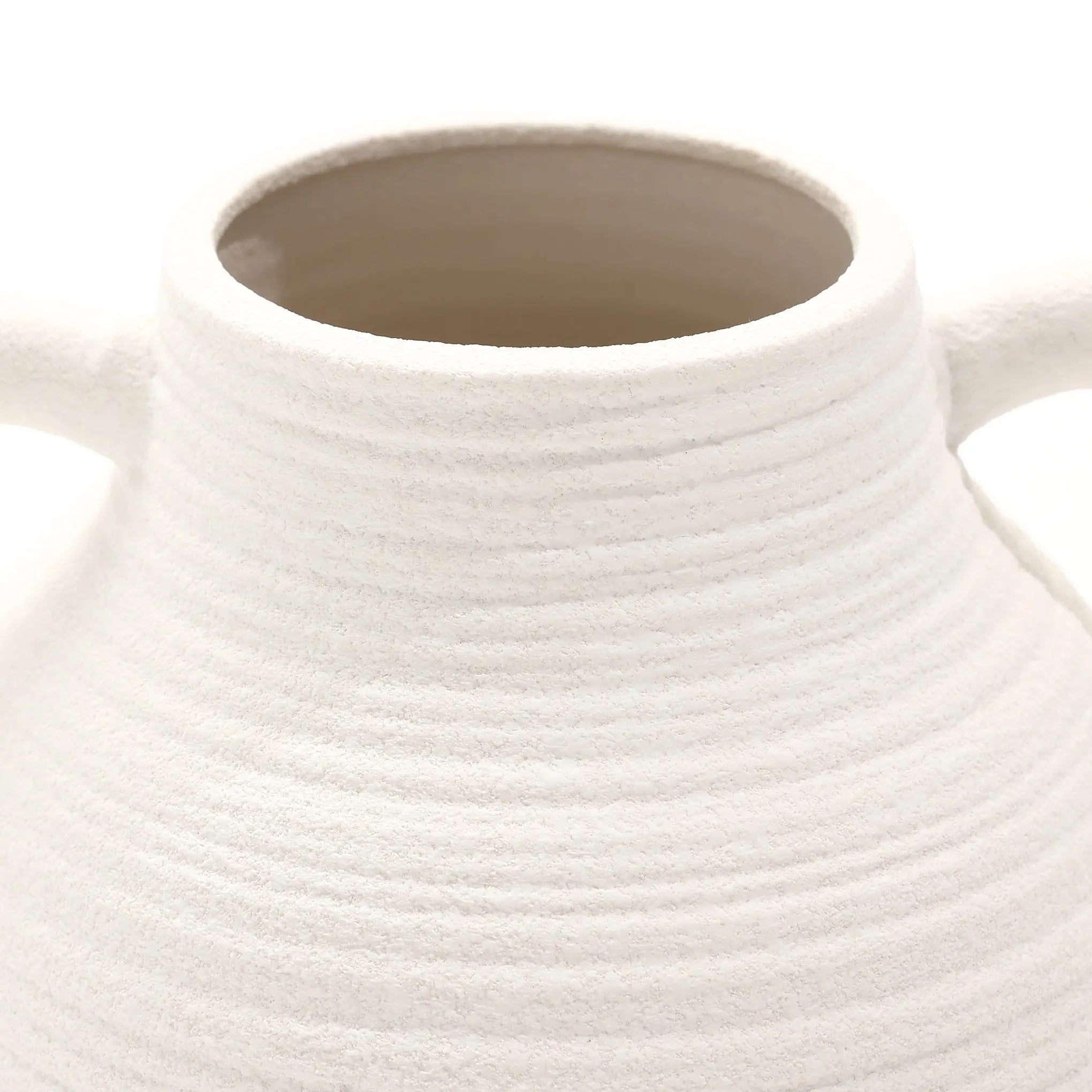 This close-up captures the rustic charm of a textured, white ceramic vase with two small handles near the top.