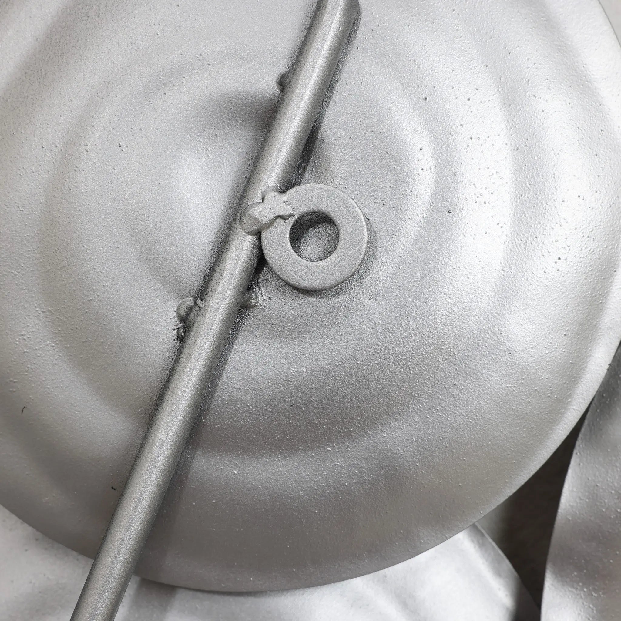 A close-up of round metal objects painted silver, curated as an abstract design with a central rod and circular attachment, perfect for modern metal wall art.