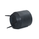 A black, round, corrugated plastic container with a distressed black finish and three support legs lies on its side against a white background.