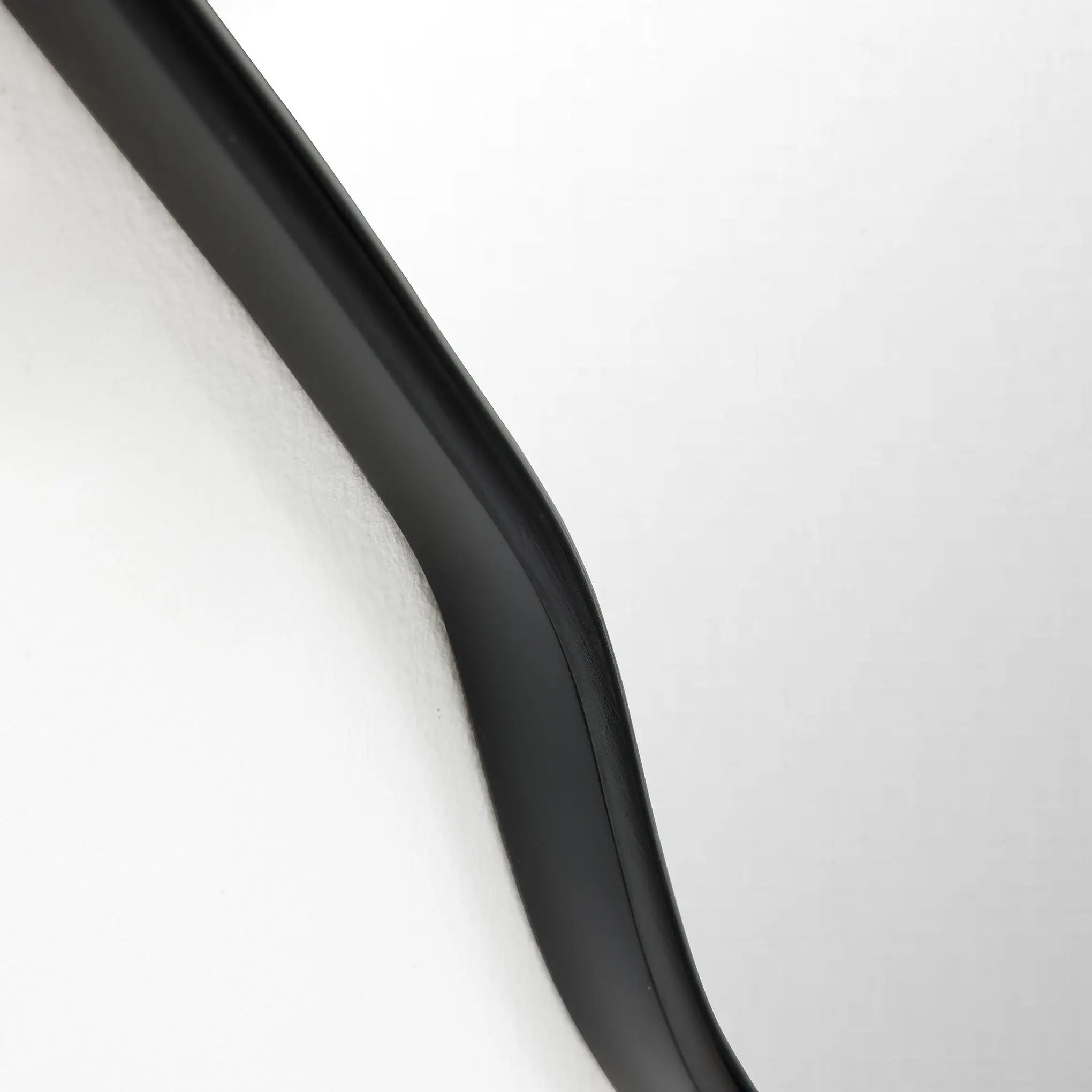 Close-up of a black, curved object against a white background, exuding a modern aesthetic with its smooth edge and gentle curve.