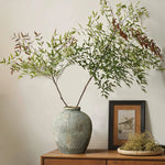 A LuxenHome rustic gold and brown terracotta bud vase (8.7 h) adorns the wooden sideboard alongside a small framed bird illustration and a shallow dish with dried flowers, elevating the home decor against an antique distressed neutral-colored wall.