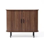 The Aria by LuxenHome is a Mid-Century Modern accent cabinet featuring tambour doors and two black metal handles. It boasts a dark oak finish with a curved front atop four slender black legs, enhancing its elegant design.