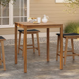 An outdoor acacia wood dining table, FSC-certified, holds a glass of milk, a jug, and a basket of bread. Surrounded by chairs on a stone patio with a beige building in the background, it offers a perfect setting for memorable meals and gatherings.