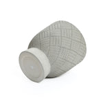 A textured gray vase crafted from MgO material lies on its side, featuring a geometric pattern and flat base.