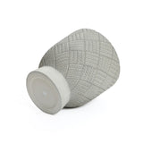 A textured gray vase crafted from MgO material lies on its side, featuring a geometric pattern and flat base.