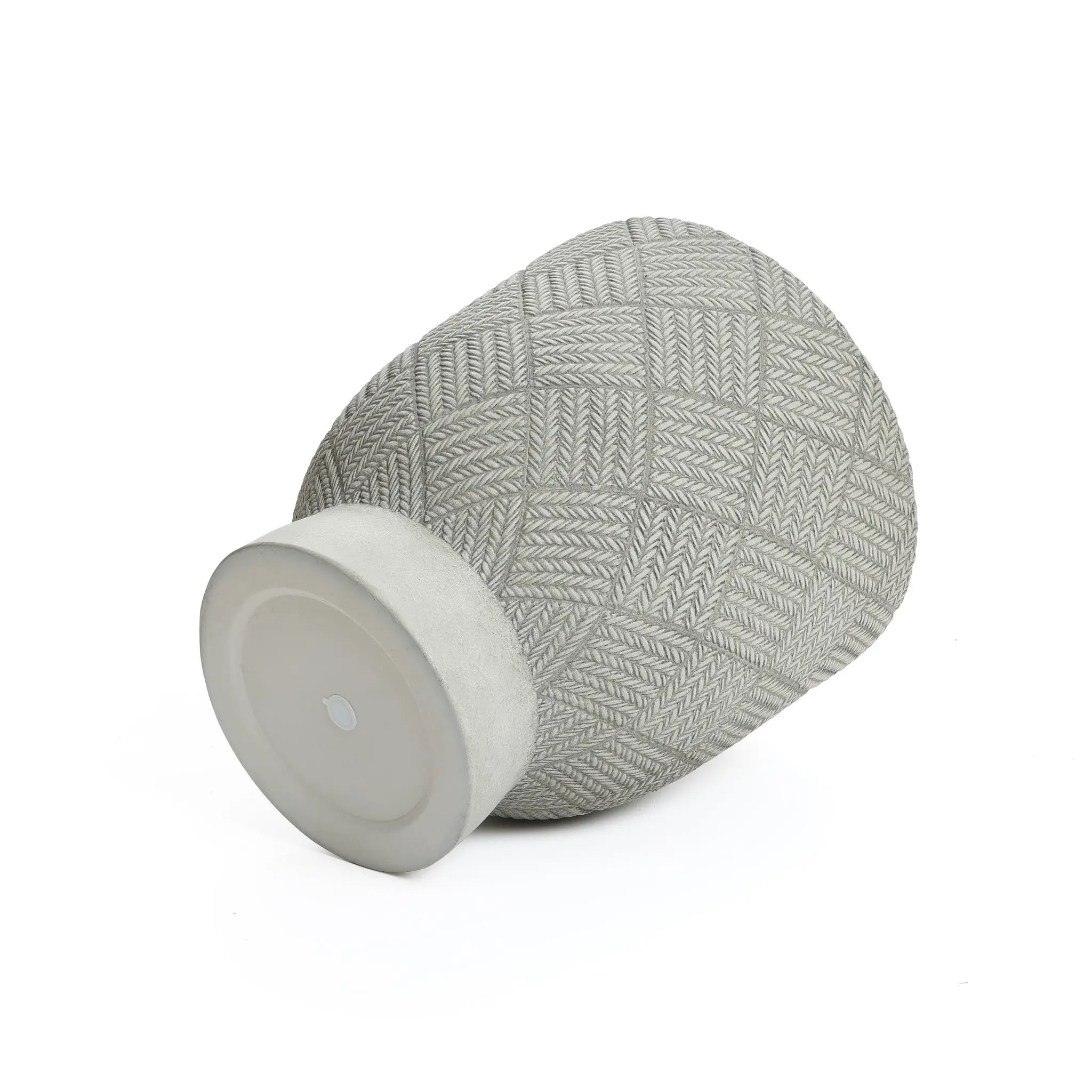 A textured gray vase crafted from MgO material lies on its side, featuring a geometric pattern and flat base.