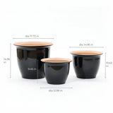 This decorative set features three glossy black planter pots of varying sizes, each labeled with dimensions for both indoor and outdoor use.