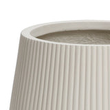 Close-up of a LuxenHome Ribbed Round Planter, 10.63 high, featuring vertical ridges and a textured exterior. The minimalist design reveals the interior from the open top.
