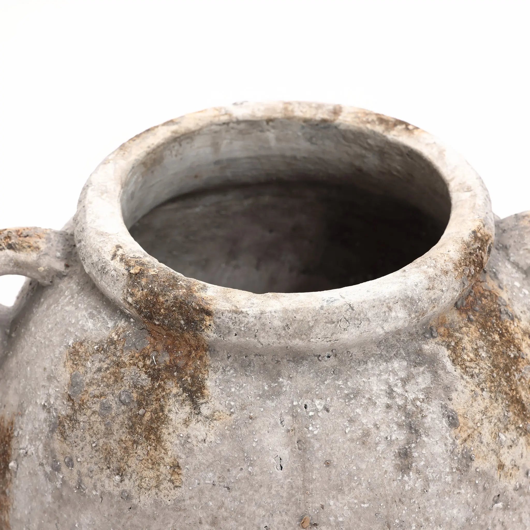 Close-up of an aged, weathered terracotta jug vase with a wide opening and small handles on a white background, exuding vintage appeal.