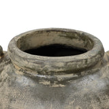 A close-up of the Fou antique terracotta vase by LuxenHome shows a rustic rim with a weathered, gray pottery finish and greenish hues, giving it an aged appearance. The pots opening reveals a dark interior.
