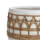 A close-up of a decorative ceramic pot with a white surface and intricate brown woven patterns, exuding a Bohemian style.