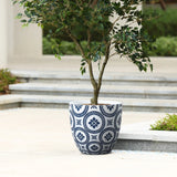 A potted tree graces the paved outdoor area, nestled in a modern planter crafted from durable MgO material, featuring an elegant blue and white design near the stairs.