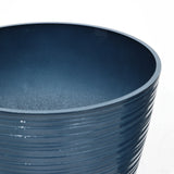 Close-up of a dark blue, textured ceramic pot with ridged patterns, perfect as a decorative planter for indoor and outdoor use. Its UV-protected finish ensures lasting beauty in any setting.
