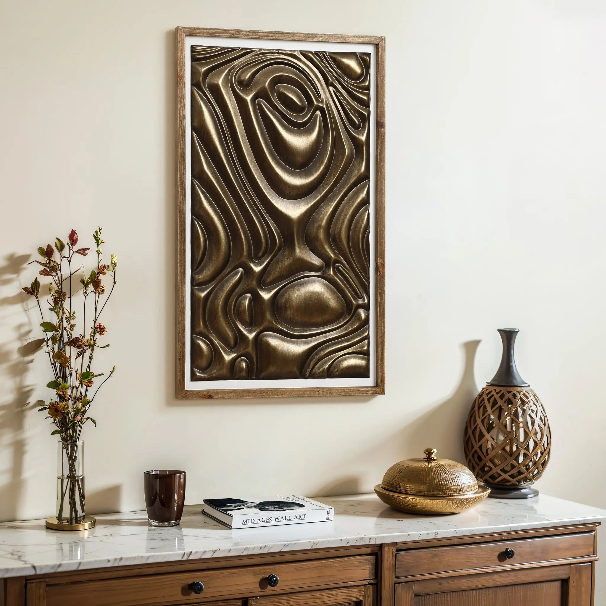 A wooden console with decorative items and a coffee table book sits beneath a framed piece of modern home decor. This gold metal abstract wall decor adds an artistic touch to the light-colored wall.