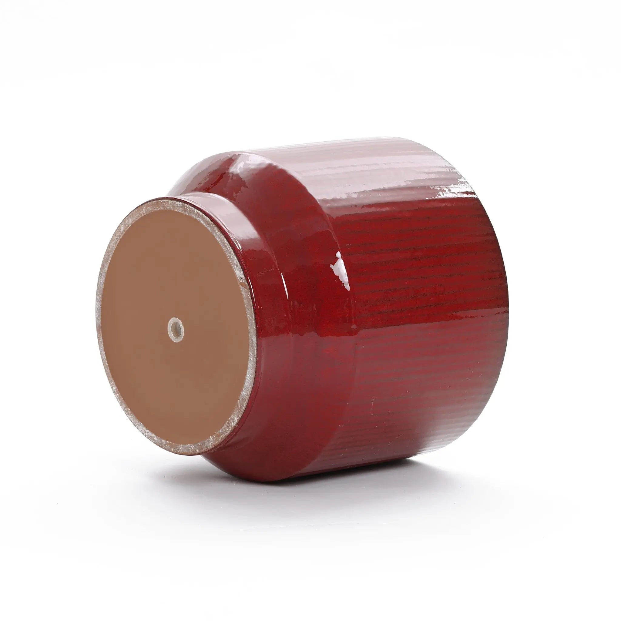 A LuxenHome burgundy red glazed round ceramic planter, 10.83 high, lies on its side against a white background. This elegant decoration features a glossy finish and an unfinished base with a drainage hole.