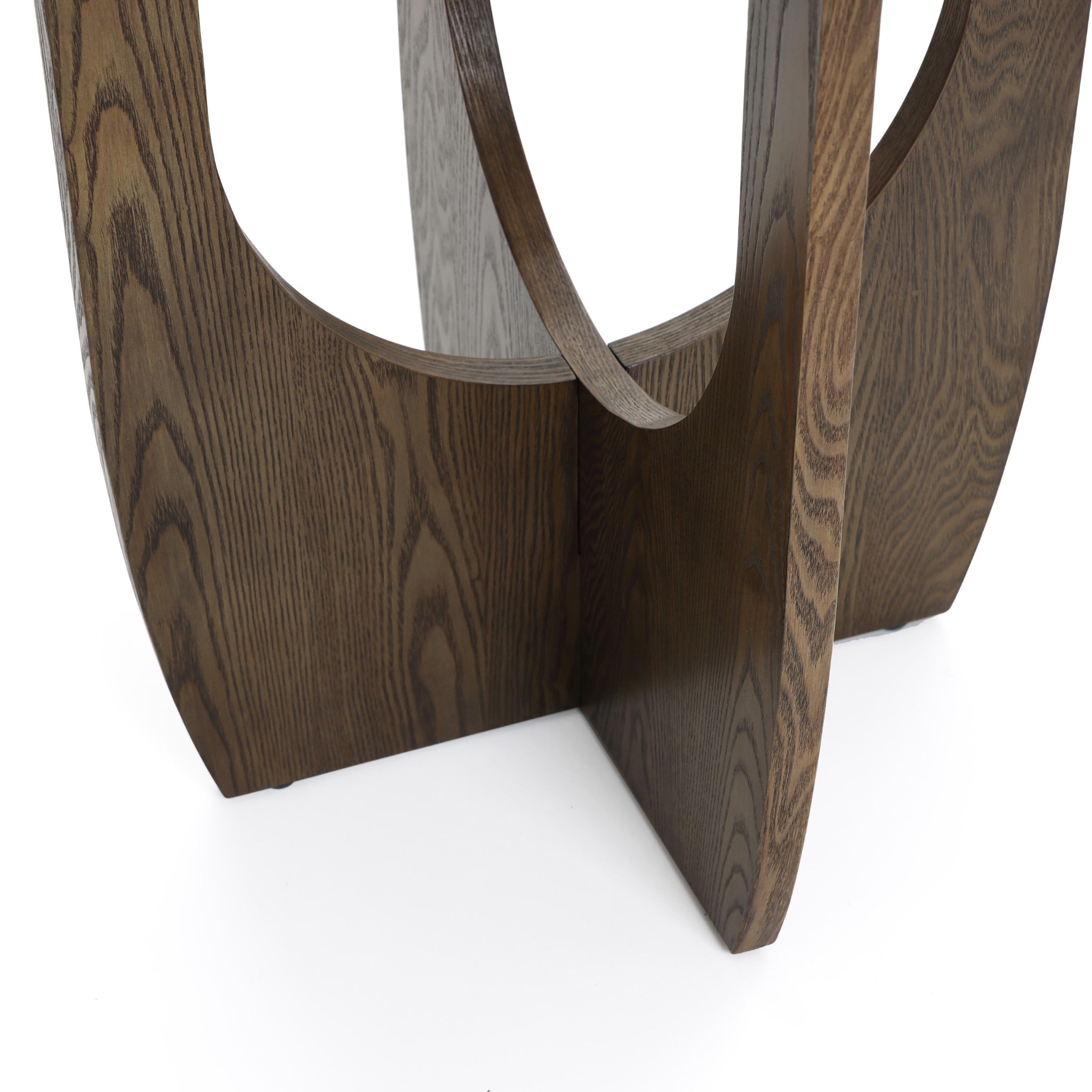A dark wooden abstract sculpture with geometric cutouts stands on a white surface, echoing the sleek elegance of a mid-century modern side table.