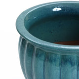 Close-up of a glossy teal ceramic decorative planter with a round rim and fluted sides. The navy blue glaze enhances its elegance, though theres a visible chip on the inside edge.