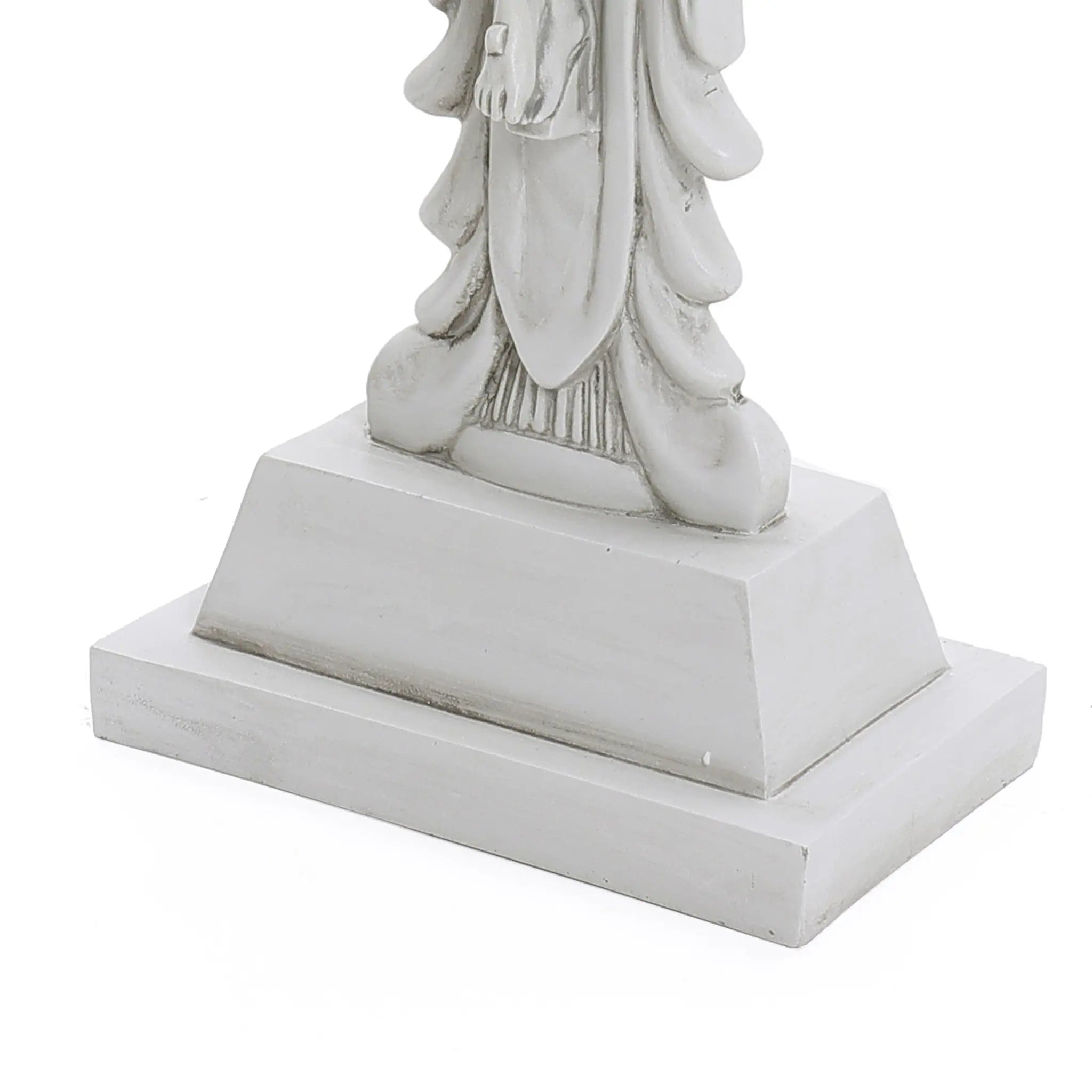 The base of a gray statue, reminiscent of a Jesus statue, features draped clothing on a rectangular pedestal against a white background.