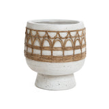 A round white ceramic planter with a speckled finish, featuring a decorative brown woven pattern around its midsection and exuding Bohemian style, sits elegantly on a flared base.