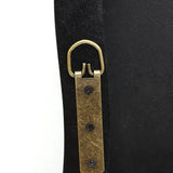 A close-up of a leather strap with an antique brass D-ring and three black screws, secured to a sleek black frame, embodies modern minimalism.