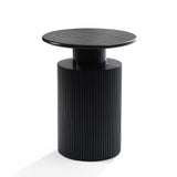 A black cylindrical side table with a ribbed base and smooth round top showcases a modern aesthetic against a white background, accented by hints of natural wood grain.