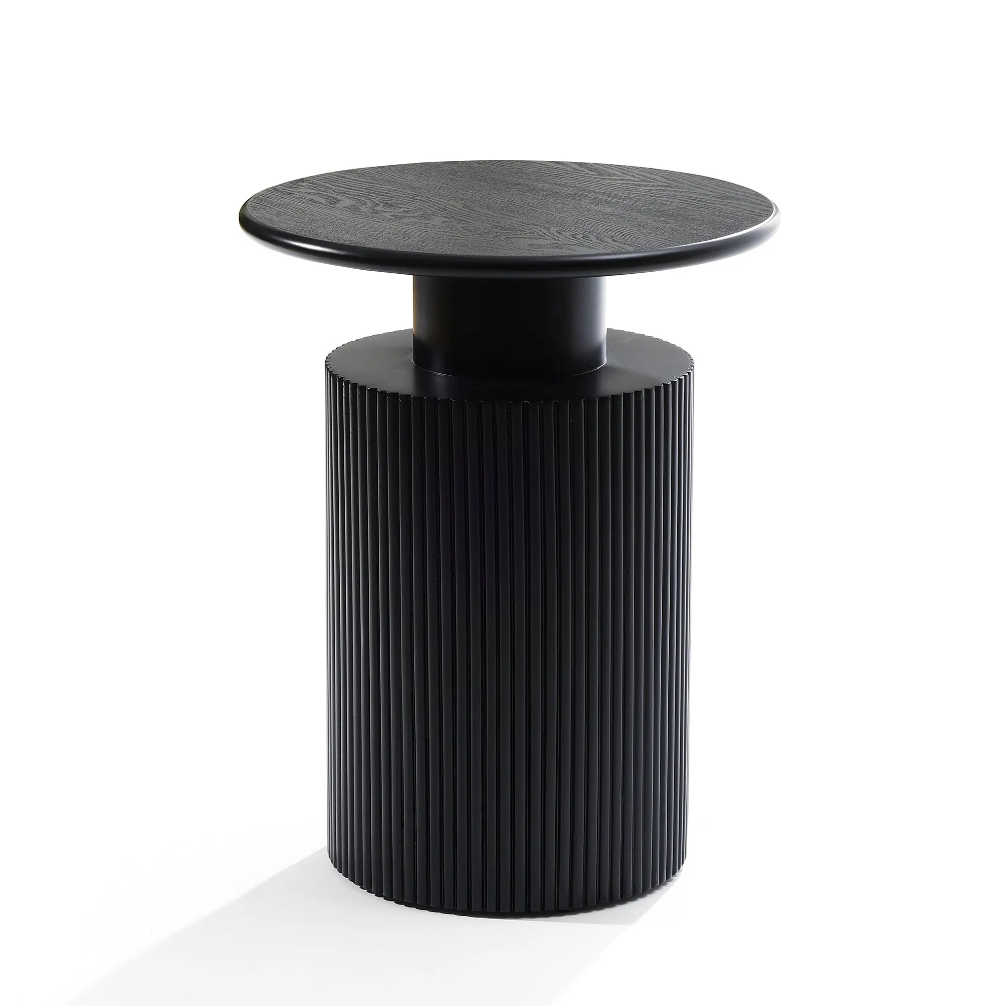 A black cylindrical side table with a ribbed base and smooth round top showcases a modern aesthetic against a white background, accented by hints of natural wood grain.