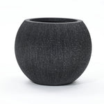 A round, textured black modern planter with a wide opening is set against a plain white background. Ideal for both indoor and outdoor spaces, this piece is crafted from durable polyethylene to withstand the elements while maintaining its sleek style.