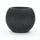 A round, textured black modern planter with a wide opening is set against a plain white background. Ideal for both indoor and outdoor spaces, this piece is crafted from durable polyethylene to withstand the elements while maintaining its sleek style.