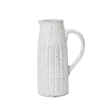 A tall, white ceramic pitcher with a handle and a textured, ribbed design exudes vintage charm, perfect as a milk jug or table vase.