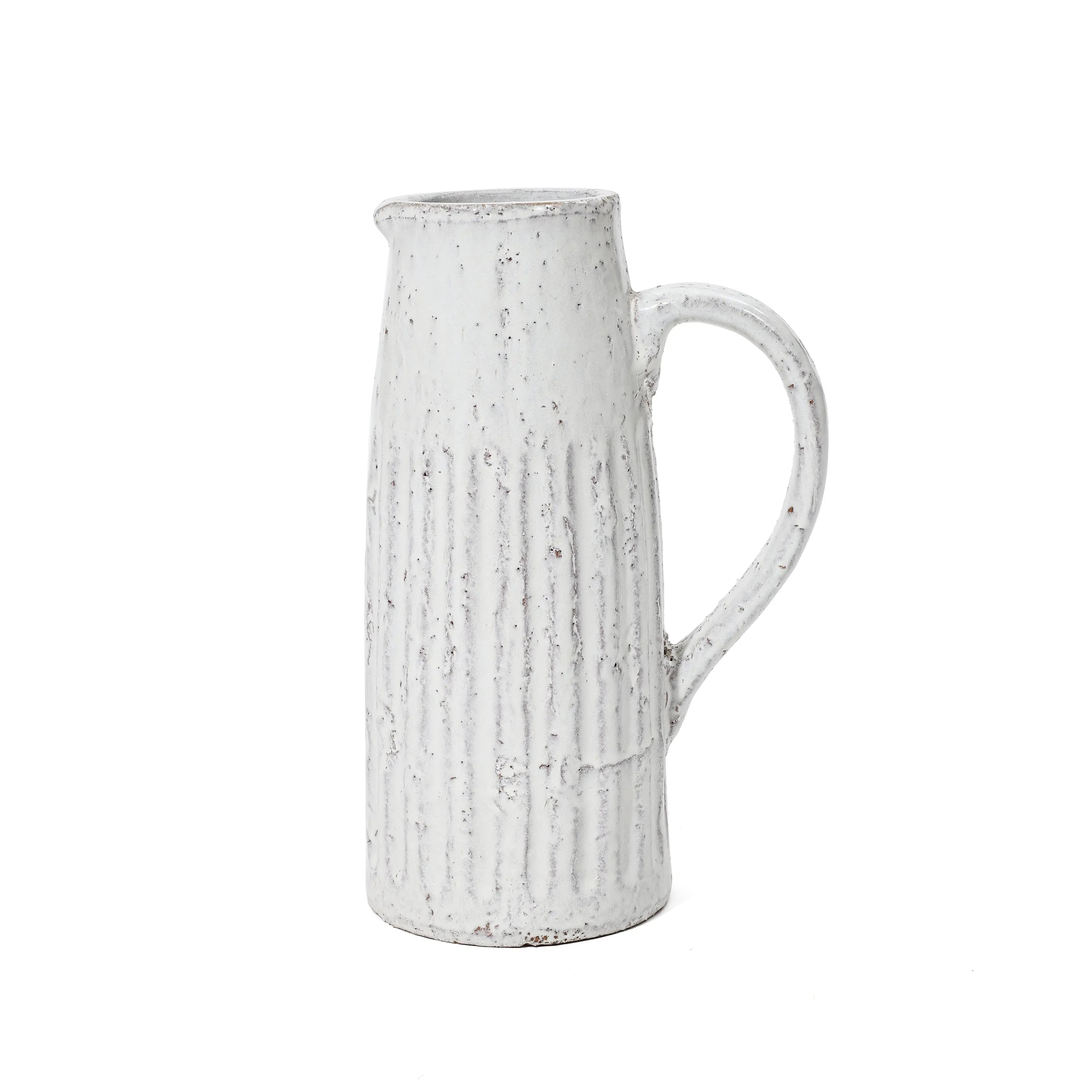 A tall, white ceramic pitcher with a handle and a textured, ribbed design exudes vintage charm, perfect as a milk jug or table vase.