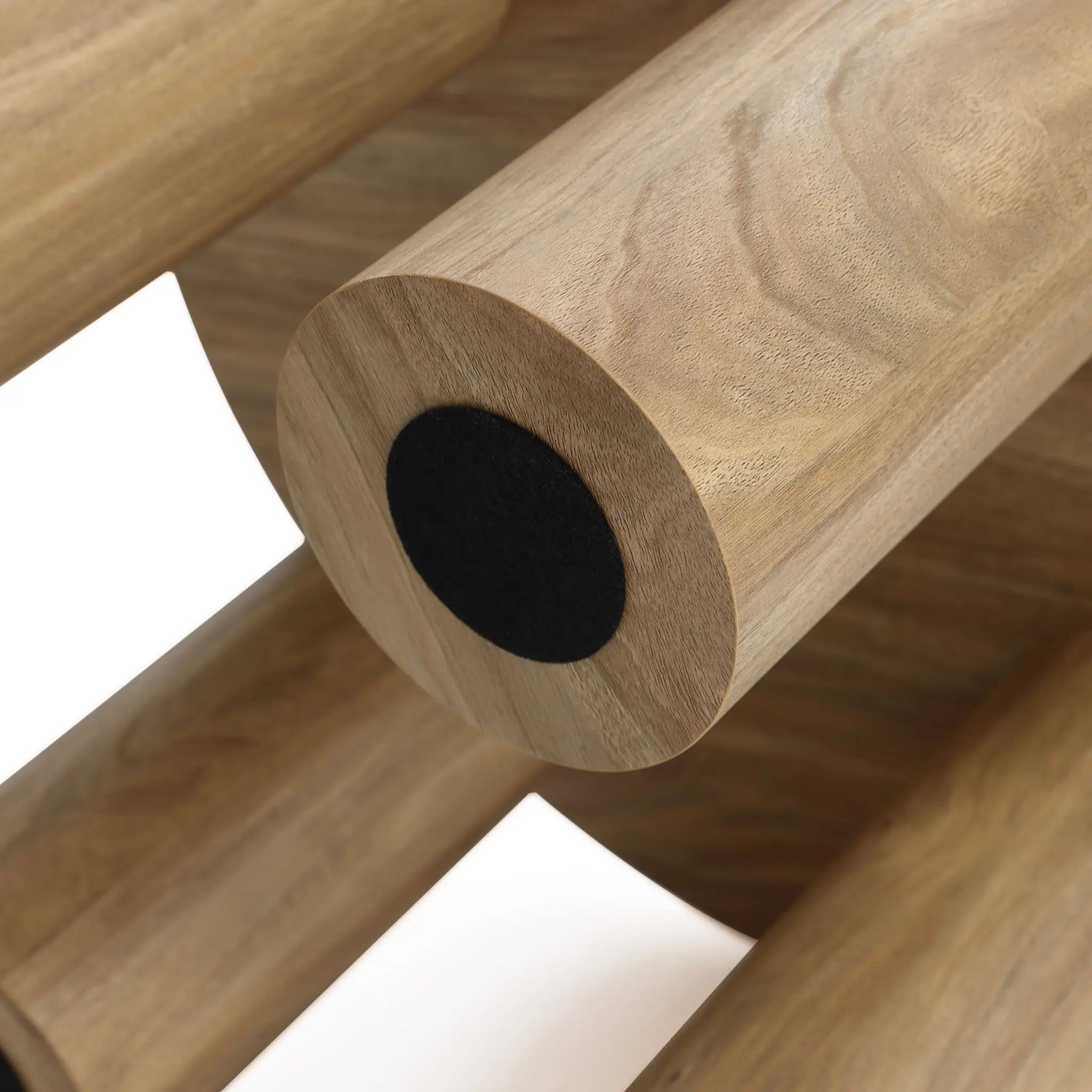 Close-up of cylindrical wooden logs stacked horizontally, showing the texture and circular black ends, reminiscent of a contemporary design coffee table base.