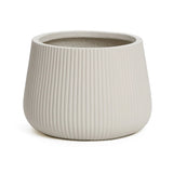 The LuxenHome Ribbed Round Planter, standing 10.63 inches tall, features a modern minimalist style with its white ceramic design and ribbed exterior. Its slightly tapered with a smooth interior, all showcased against a plain white backdrop.