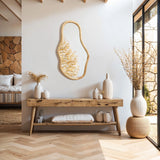 A minimalist living space features a wooden console table with vases and an irregular oval-shaped mirror as a decorative statement. Sunlight streams through a large window, illuminating the wicker pouf and highlighting elements of natural pine wood.