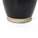 Close-up of a dark, glossy ceramic pot with black glaze and a rough, unglazed base on a white background, showcasing its handcrafted artistry.