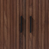 The LuxenHome Aria 2-Door Tambour Accent Cabinet features a close-up of its dark oak finish with vertical grooves and sleek black handles, enhancing its luxurious Mid-Century Modern appeal.