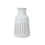 A white ceramic vase exuding rustic charm with vertical ridges and a narrow neck, reminiscent of a vintage design.