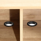 Two black circular grommets in a wooden surface, positioned side by side on an elegant oak TV stand.