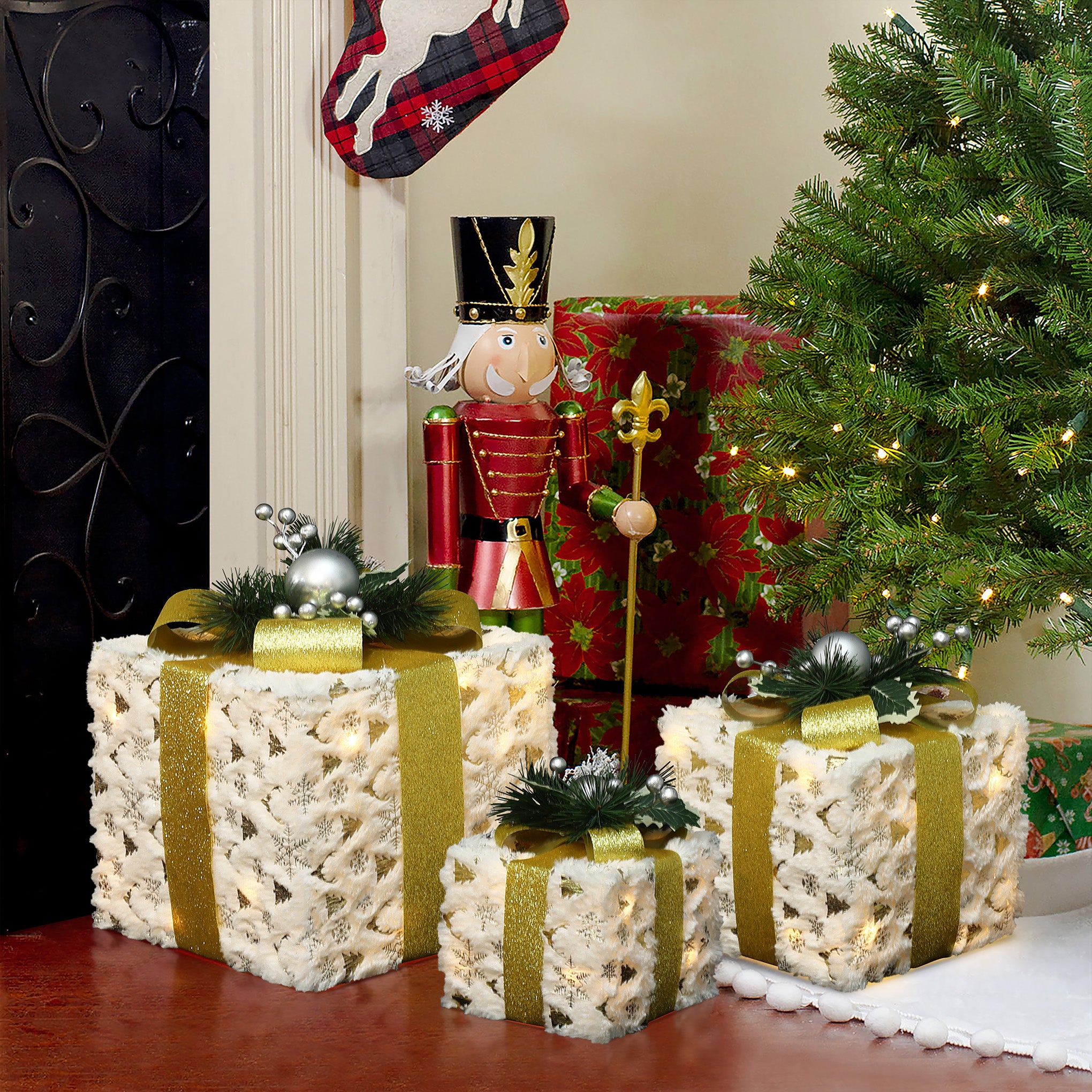 3 Christmas Decor Gift Boxes with gold ribbons sit beside a tree ,a nutcracker.