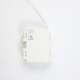 White rectangular plastic box with wire attached, featuring printed text that reads 1. ON 2. OFF on the frontns.