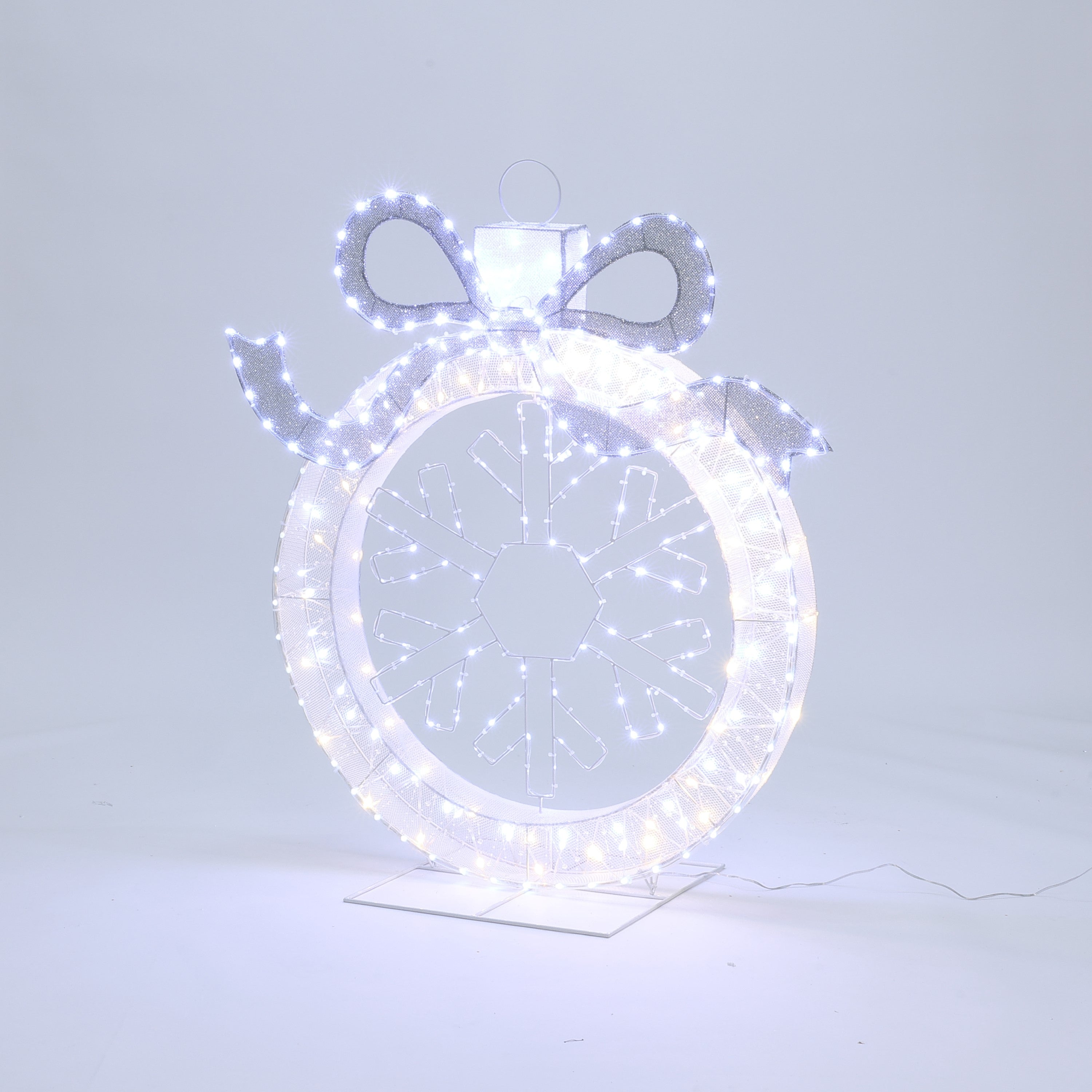 Large decor ornament shaped like a christmas bauble with snowflake design, outlined by bright white led lights.