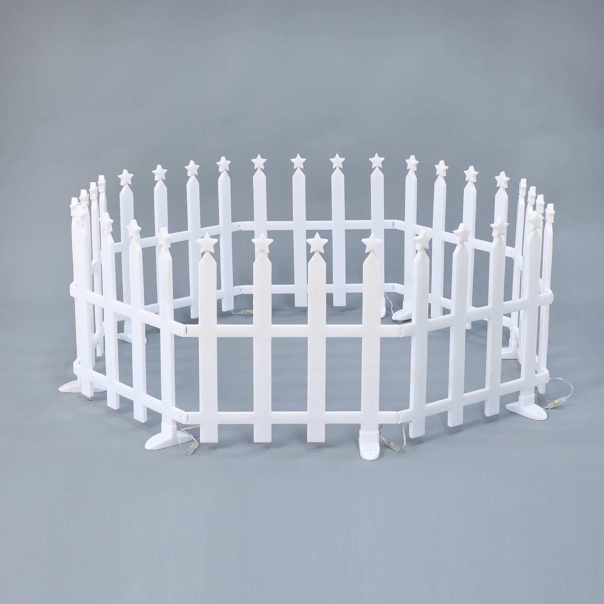 Small, white, circular picket fence with star-shaped tops on each post, set against plain gray background.